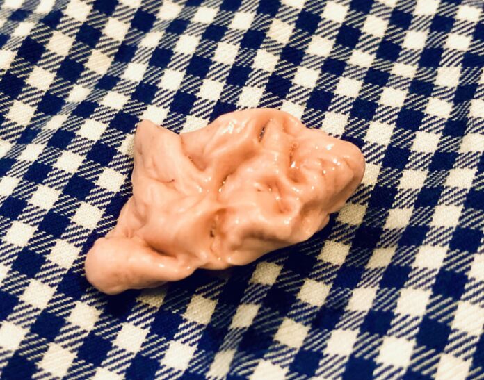 Sur l'image, on voit un chewing-gum rose sur une nappe.