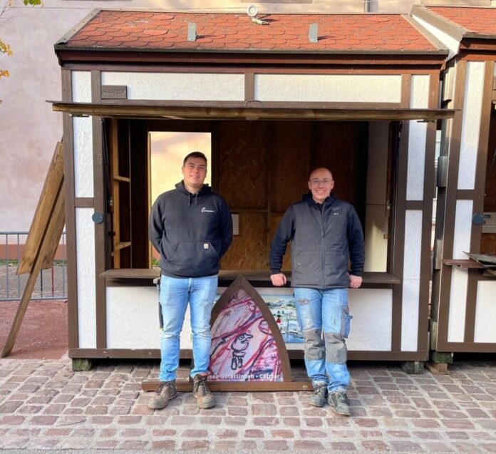 Léo Mattern (à gauche) et Thierry Fricker (à droite) devant un chalet de Noël qu’ils ont installé à Colmar.